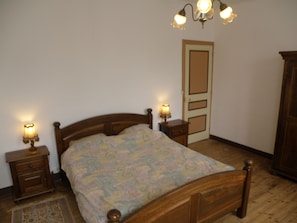 Une chambre à coucher avec un lit en bois, deux tables de chevet avec des lampes, une porte et une armoire.