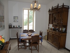 Une salle à manger avec une table dressée pour quatre personnes, un lustre et un buffet en bois orné de sculptures complexes.