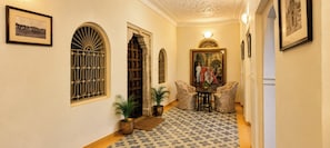 A hallway with arched windows, a framed painting, and patterned flooring.