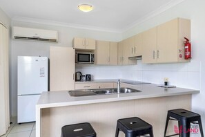 A modern kitchen with a central island, stainless steel appliances, and light wood cabinetry. - Flinders Peak Estate-Country Villa (Peak Crossing)