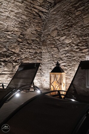 A stone-walled room with a single lit lantern and two reclining chairs.