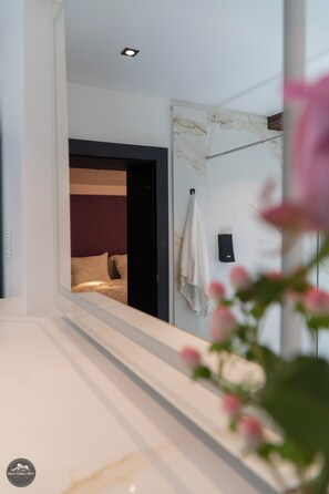 Un baño moderno con pared de mármol, un perchero y una zona de ducha visible.