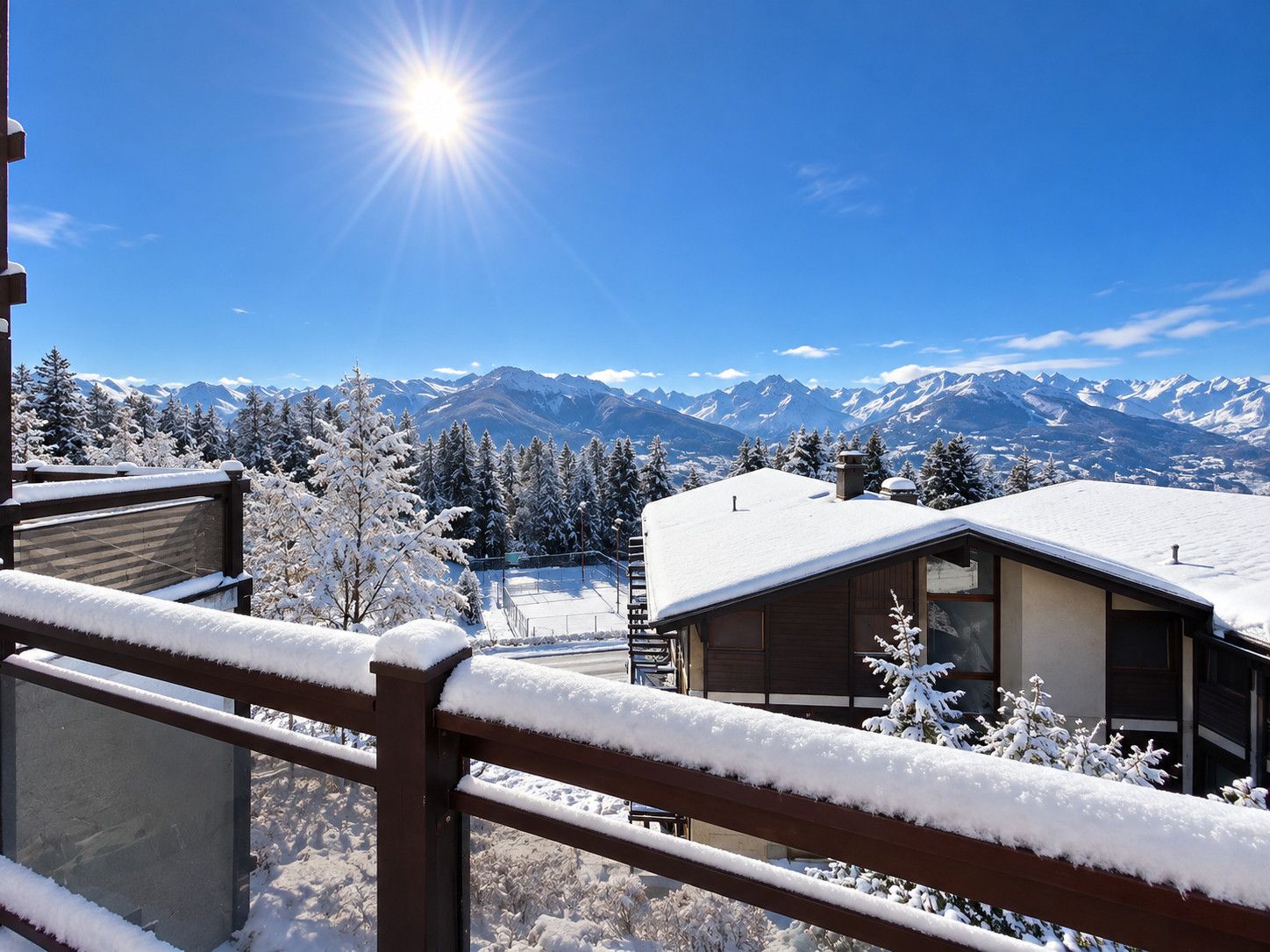 A snow-covered mountain landscape with a clear sky and a bright sun.