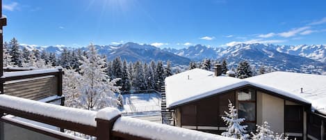 A snow-covered mountain landscape with a clear sky and a bright sun.