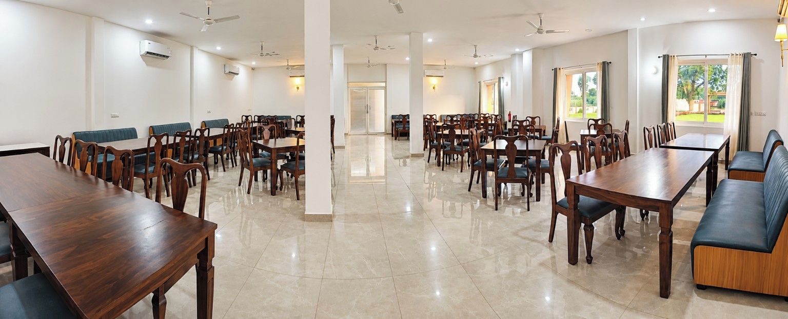 Un grand espace dédié à la salle à manger, avec plusieurs tables et chaises, des unités de climatisation et une vue sur l’extérieur.