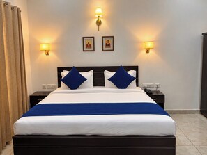 A hotel room with a bed, two bedside tables, a nightstand, a lamp, and a curtain. - VITS Select Kailasha Garden Ayodhya (Sarairasi Uparhar)