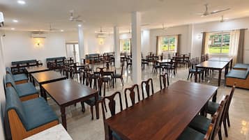 Un comedor amplio con múltiples mesas y cabinas, ventiladores de techo y grandes ventanas que aportan luz natural.
