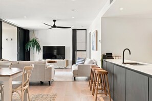 Ein modernes Wohnzimmer mit einer Couch, einem Esstisch und einem Fernseher.