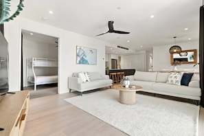 Een moderne woonkamer met een bank, salontafel en plafondventilator.