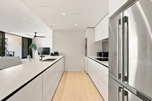 Eine moderne Küche mit weißen Schränken, einem Edelstahlkühlschrank und Holzboden.
