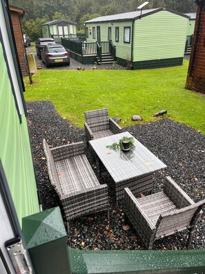 A patio area with wicker furniture and a table, surrounded by gravel. - Harmony | Cosy 3BR Retreat in Windermere | Pet Friendly (Middleton)