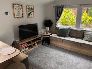 Uma sala de estar com sofá, televisão, mesa de centro e estante de livros.