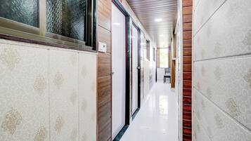 Un pasillo con paredes estampadas, techo de madera y piso blanco.