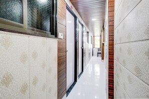 A hallway with patterned walls, a wooden ceiling, and a white floor. - Hotel O Amma Bhau Residency (Mumbai)