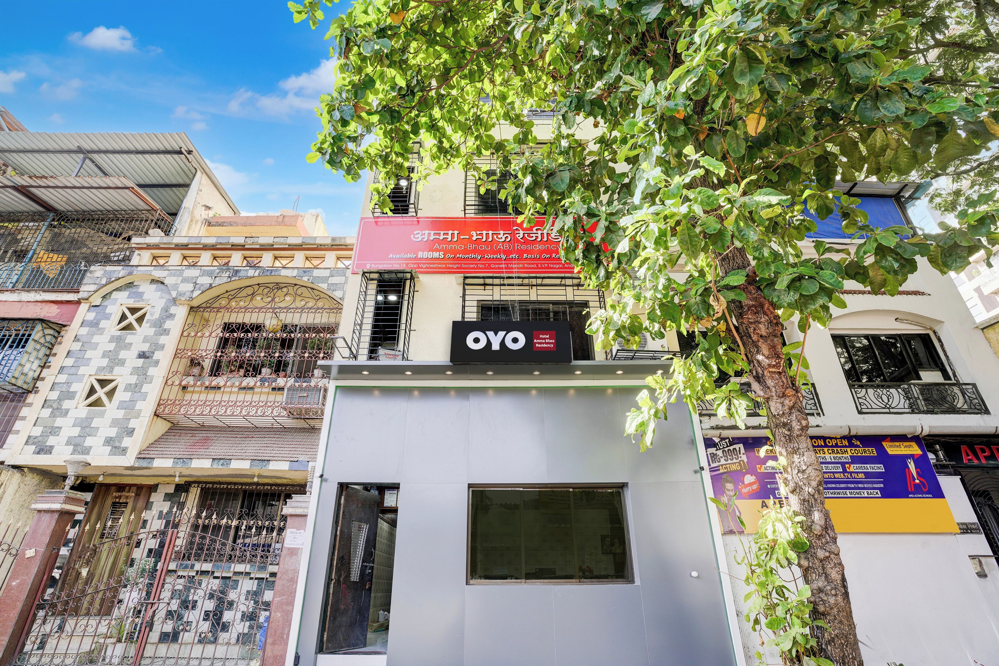Un edificio con un letrero que anuncia 'Amma-Bhau (AB) Residency', ofreciendo habitaciones disponibles por mes.