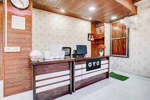 Un mostrador de recepción con un reloj, una computadora y el letrero de recepción.