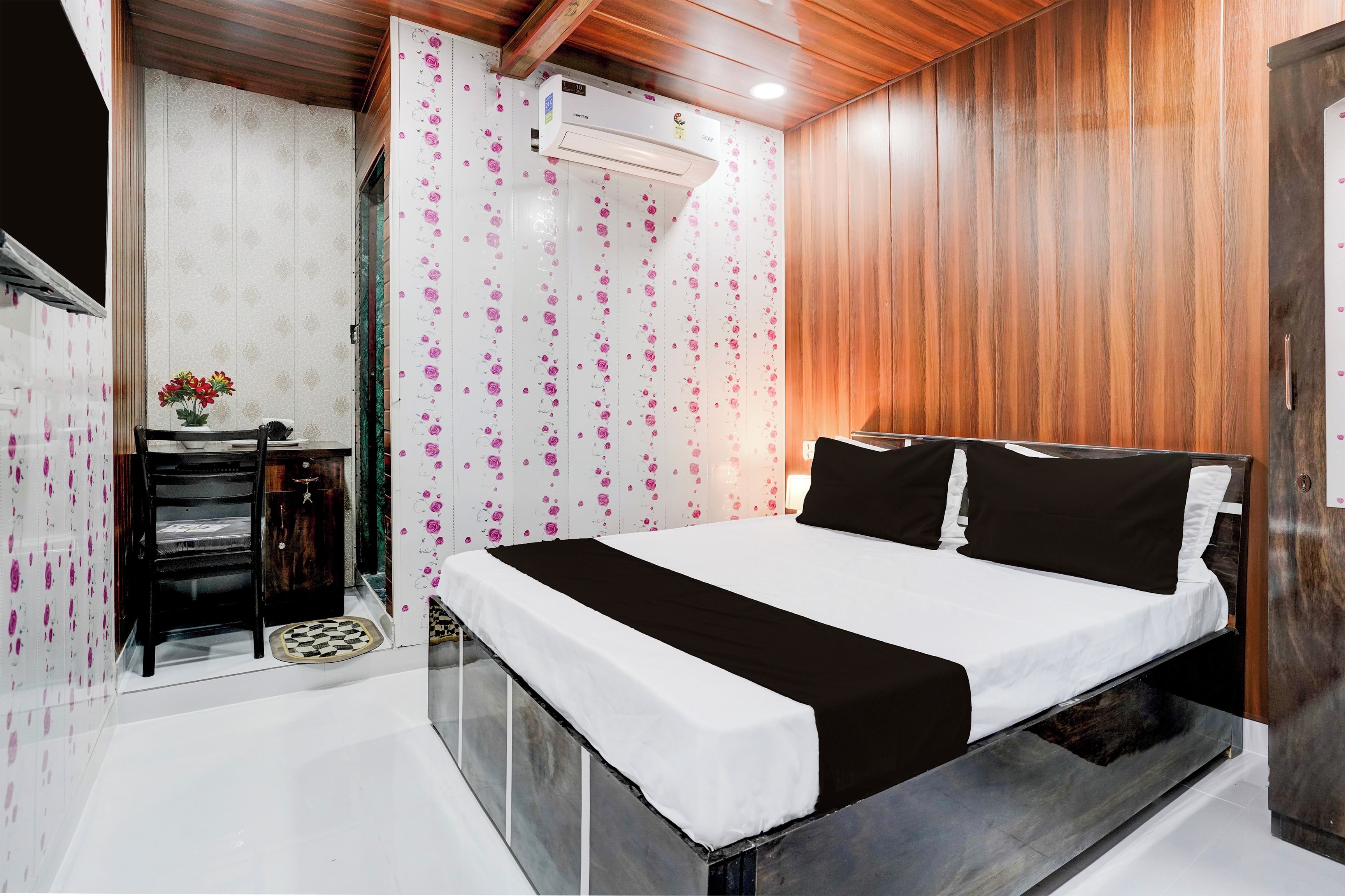 A bedroom with a bed, a wardrobe, a vanity, and an air conditioning unit.