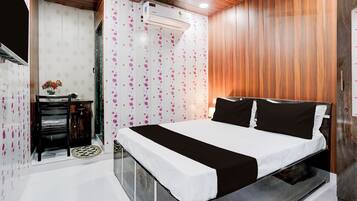 A bedroom with a bed, a wardrobe, a vanity, and an air conditioning unit.