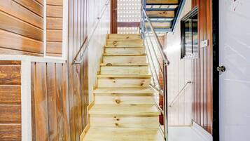 Una escalera de madera con barandillas de metal que conduce a una puerta con un ventanal esmerilado.