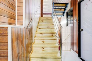 A wooden staircase with metal handrails leading to a door with a frosted glass window. - Hotel O Amma Bhau Residency (Mumbai)