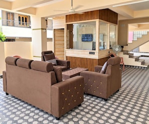 A modern reception area with a reception desk, seating, and a staircase. - Classic Tirumala Hill View Tirupati (Tirupati)