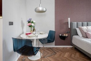 Ein gemütlicher Raum mit einem Bett, einem Esstisch mit Stühlen, einer Pendelleuchte und einem kleinen Nachttisch mit Kerzen.