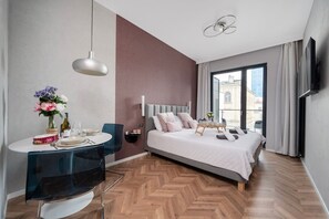 Een moderne hotelkamer met een bed, een eethoek en een groot raam.