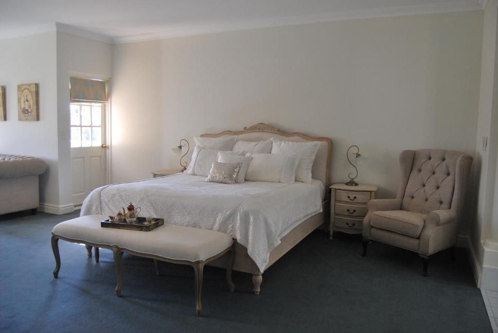 A bedroom with a large bed, a bedside table, a chair, and a bench.