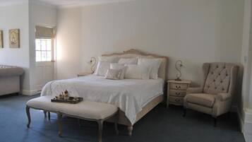 A bedroom with a large bed, a bedside table, a chair, and a bench.