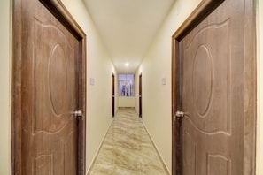 Un passadís amb portes de fusta i un paviment de marbre, que condueix a una habitació amb finestra.