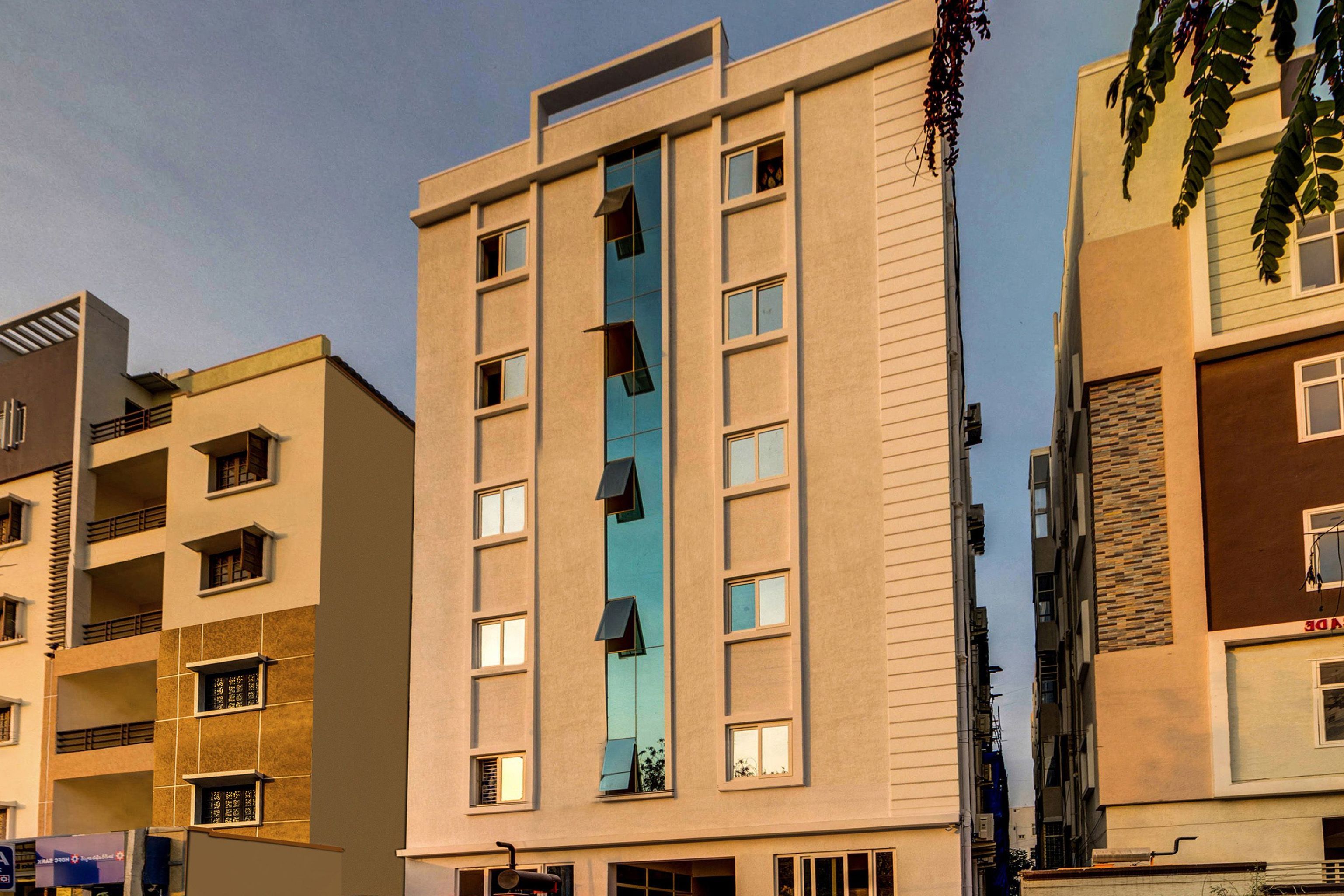 Un edificio de varios pisos con un hueco central para ascensor, múltiples ventanas y balcones.