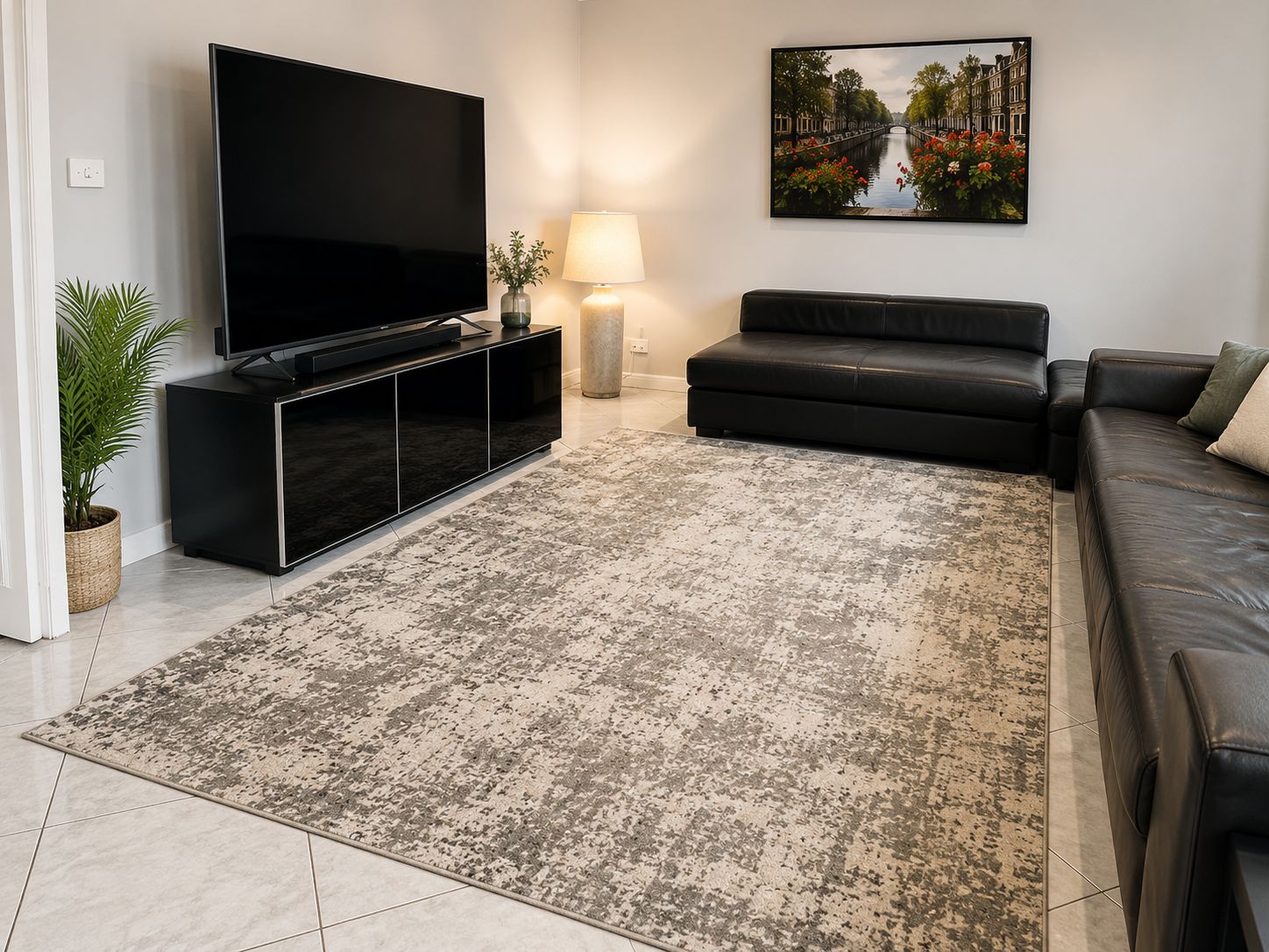 Una sala de estar con un televisor de pantalla plana, un sofá, un tapete y un cuadro en la pared.