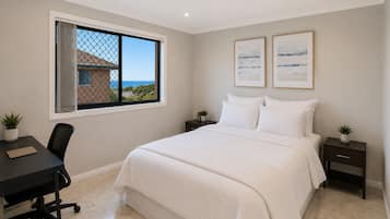 A bedroom with a bed, a desk, and a window with a view.