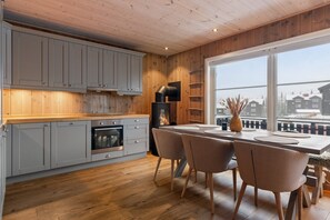 Ett modernt kök med grå skåp, en träbänkskiva och en matplats med ett bord och stolar.