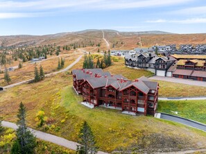 A lodge with multiple buildings, a paved road, and a hilly landscape in the background. - FA301 Top-Floor flat with Sauna, Three Balconies (Trysil)