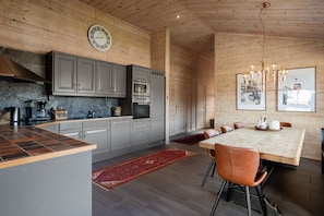 A modern kitchen with grey cabinets, a built-in oven, and a dining area with a large table and chairs. - FA301 Top-Floor flat with Sauna, Three Balconies (Trysil)