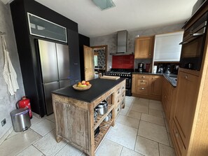 Eine Küche mit einer Holzinsel, Edelstahlgeräten und einer roten Spritzschutzwand.