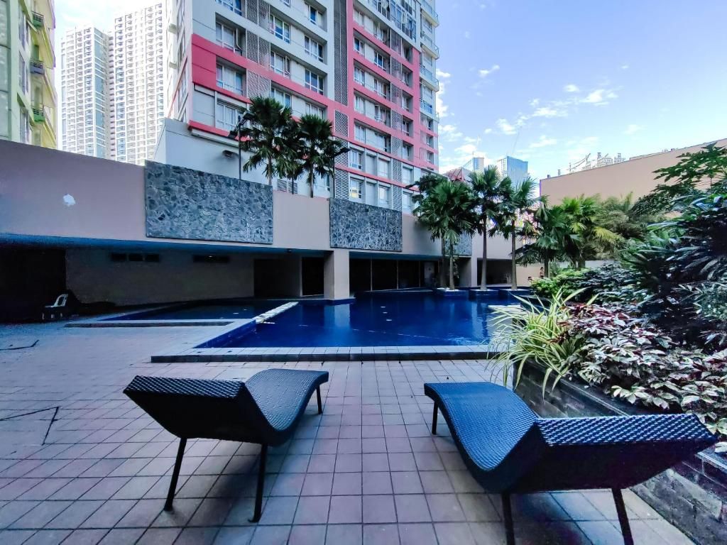 A rooftop pool area with lounge chairs, a swimming pool, and surrounding greenery.