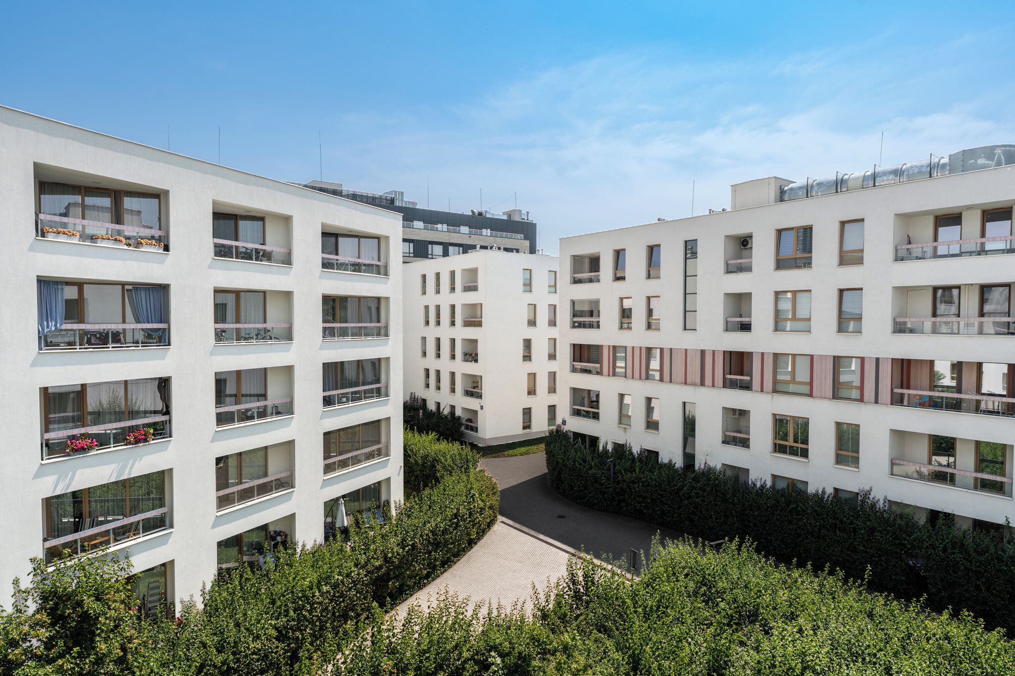 Ein moderner Wohnkomplex mit mehreren Etagen, Balkonen und einem Innenhof.