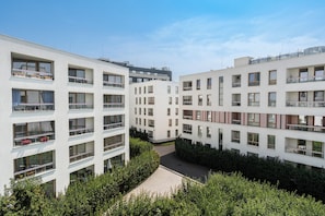 Ein moderner Wohnkomplex mit mehreren Etagen, Balkonen und einem Innenhof.