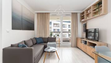 Una sala de estar moderna con un sofá gris, una mesa de centro, un televisor y un mueble de madera.