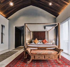 A four-poster bed with a wooden frame, a bench at the foot, and a patterned rug. - Villa Sarai is the most beautiful villa on KS & won awards because of its beauty (Koh Samui)