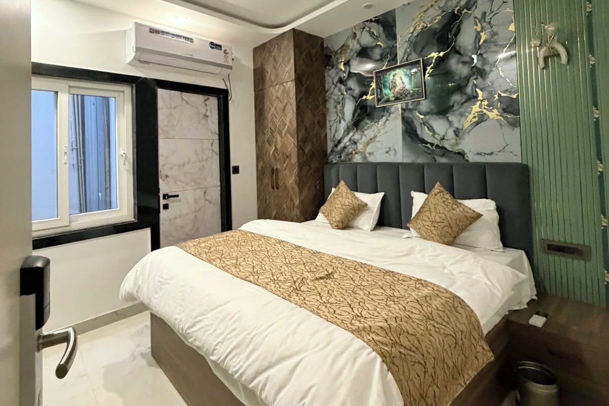 A modern bedroom with a large bed, a marble wall mural, and a green accent wall.