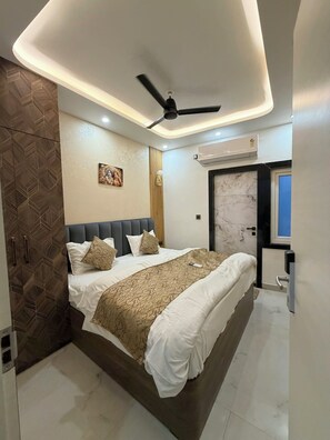 A modern bedroom with a bed, a ceiling fan, and an air conditioning unit. - Nandani Palace (Ayodhya)