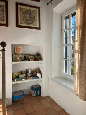 A room with a window, shelves with various items, and a tiled floor. - Vrbo Property (Piemonte)