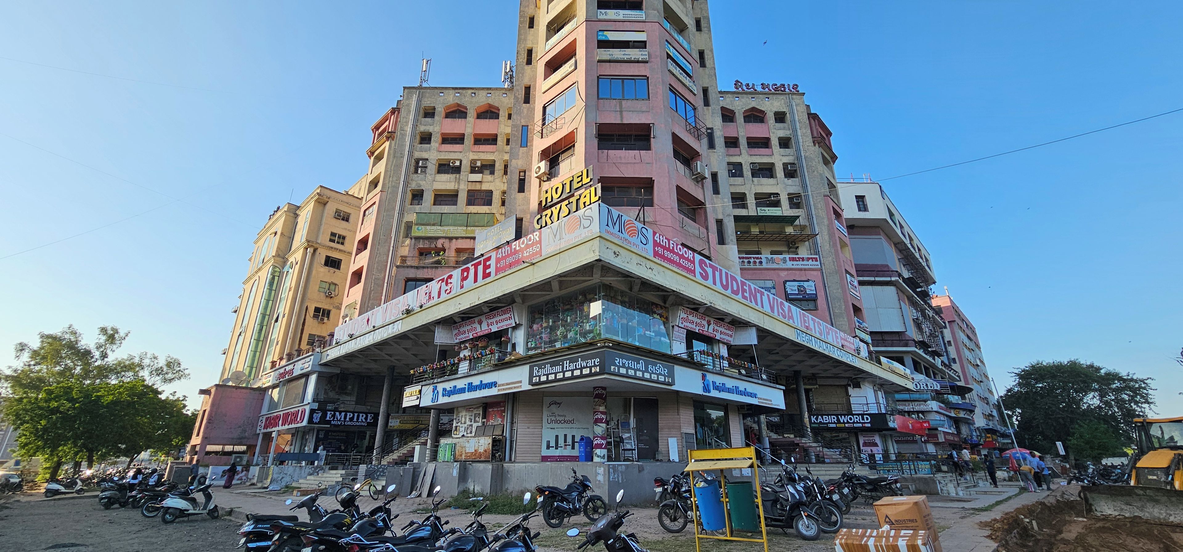 A multi-story building with various commercial establishments on the ground floor, including a hotel, a student visa service, and a hardware store.