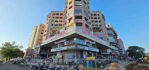 A multi-story building with various commercial establishments on the ground floor, including a hotel, a student visa service, and a hardware store. - Hotel Crystal N (Gandhinagar)