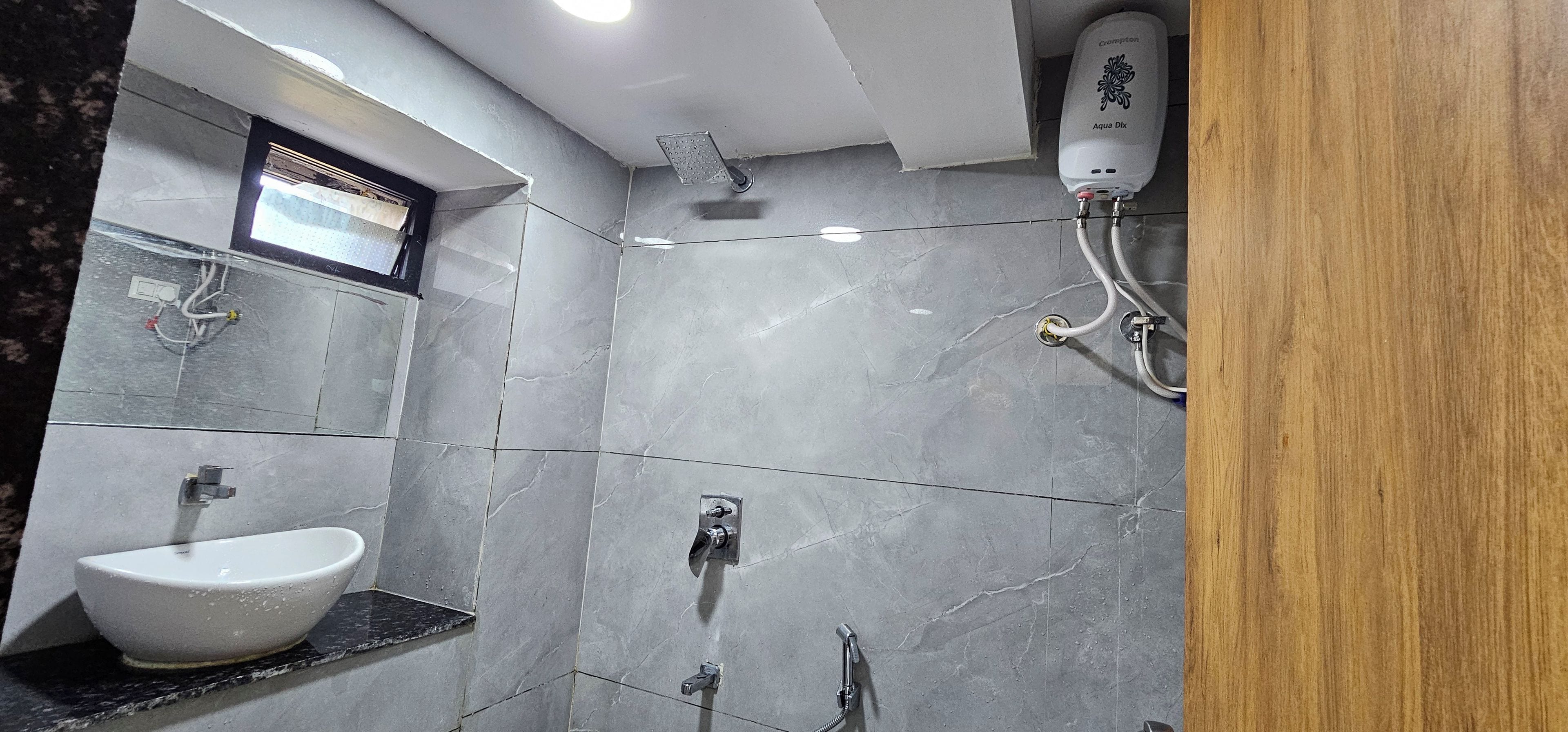A bathroom with a white sink, a shower, and a wall-mounted water heater.
