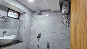 A bathroom with a white sink, a shower, and a wall-mounted water heater.