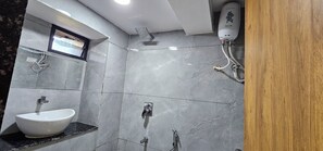 Un baño con lavamanos blanco, ducha y calentador de agua instalado en la pared.